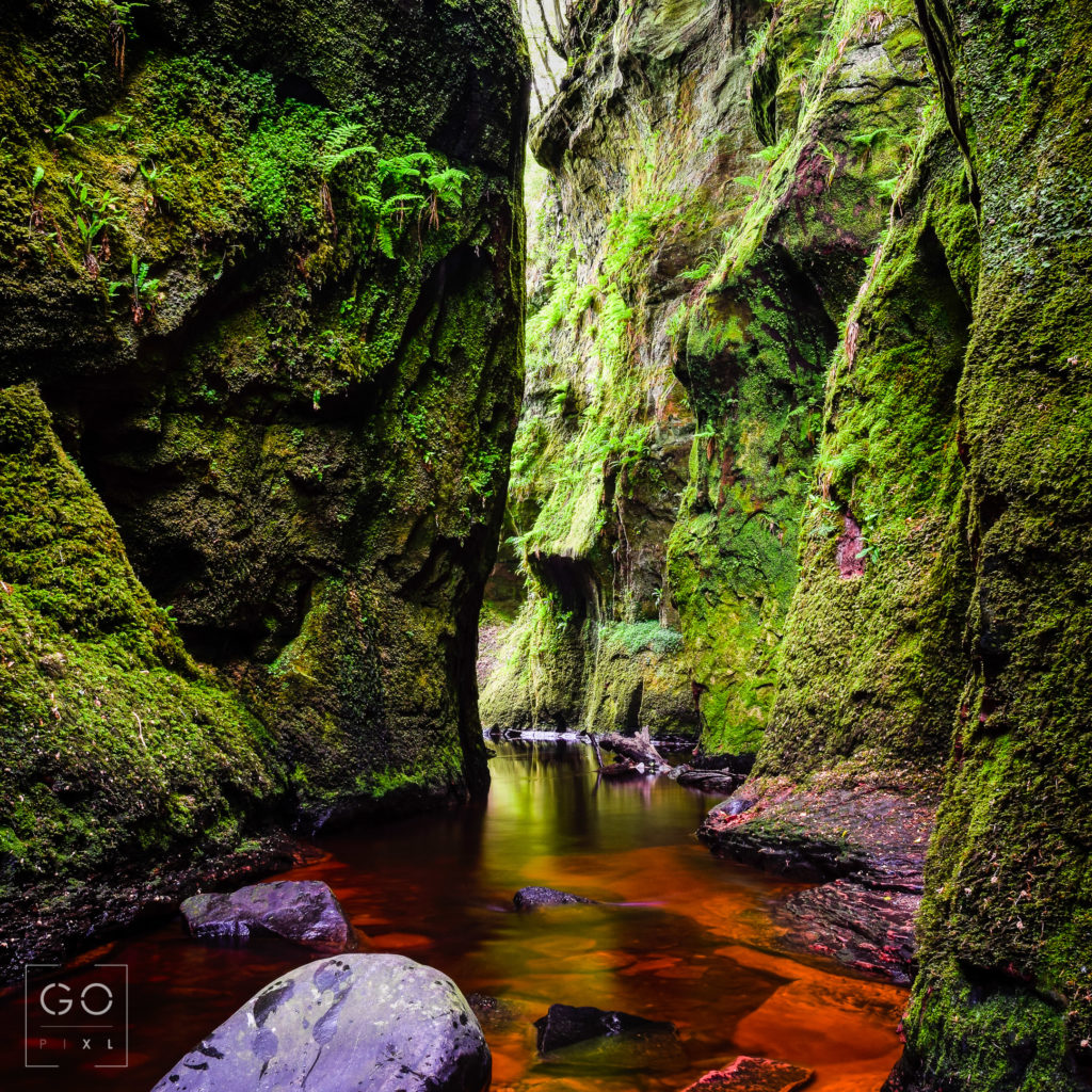 A lovely canyon in Scotland where the green of the moss contrasts with the blood red water
